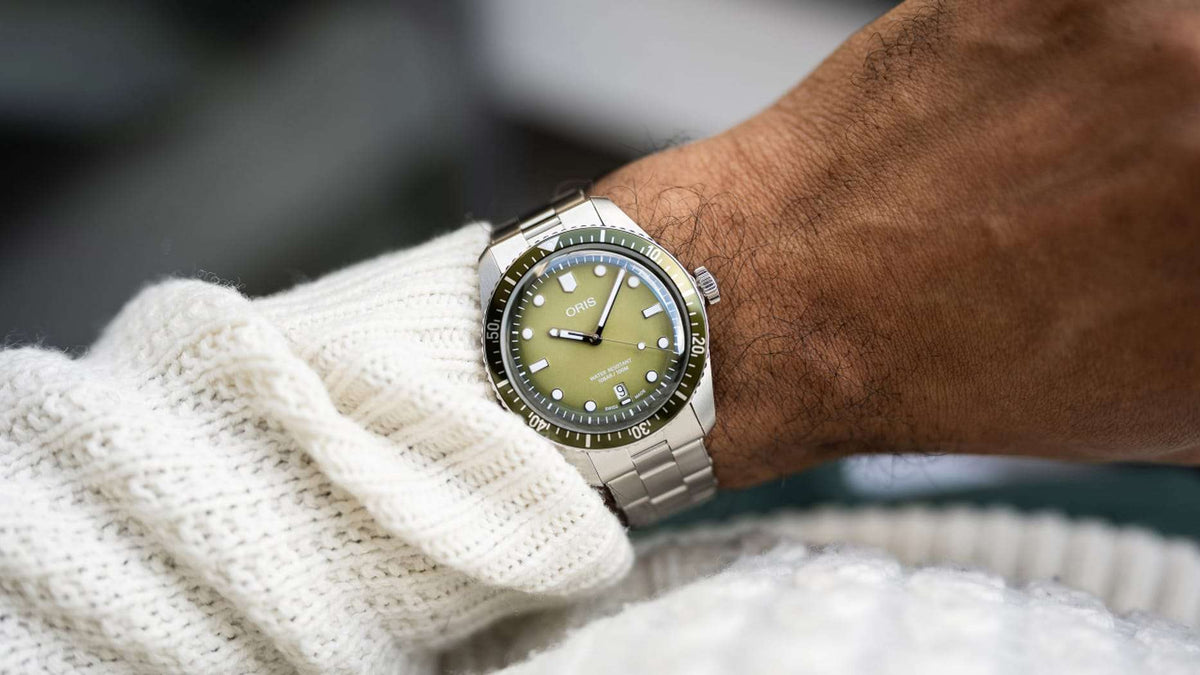 Orologio subacqueo ORIS con quadrante verde e bracciale in acciaio, al polso