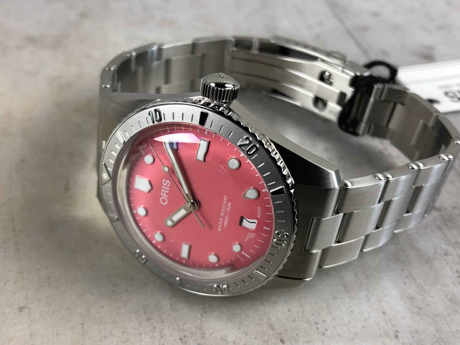 Orologio ORIS su fondello e bracciale in acciaio; quadrante rosso con indici a bastone.