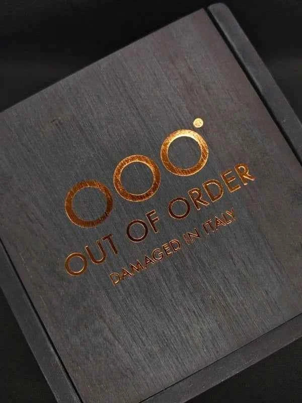 Scatola Out of Order con scritta arancione su coperchio grigio, design diamantato