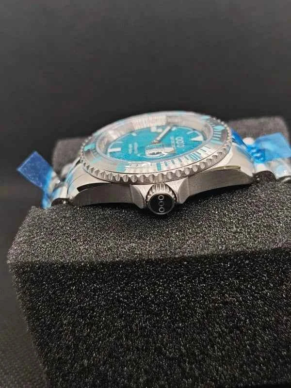 Orologio subacqueo visto di lato con corona e quadrante blu-verde su bracciale acciaio