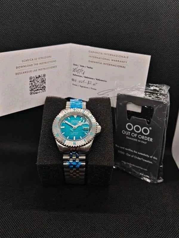 Orologio subacqueo con quadrante blu-verde, bracciale acciaio e accessori di corredo