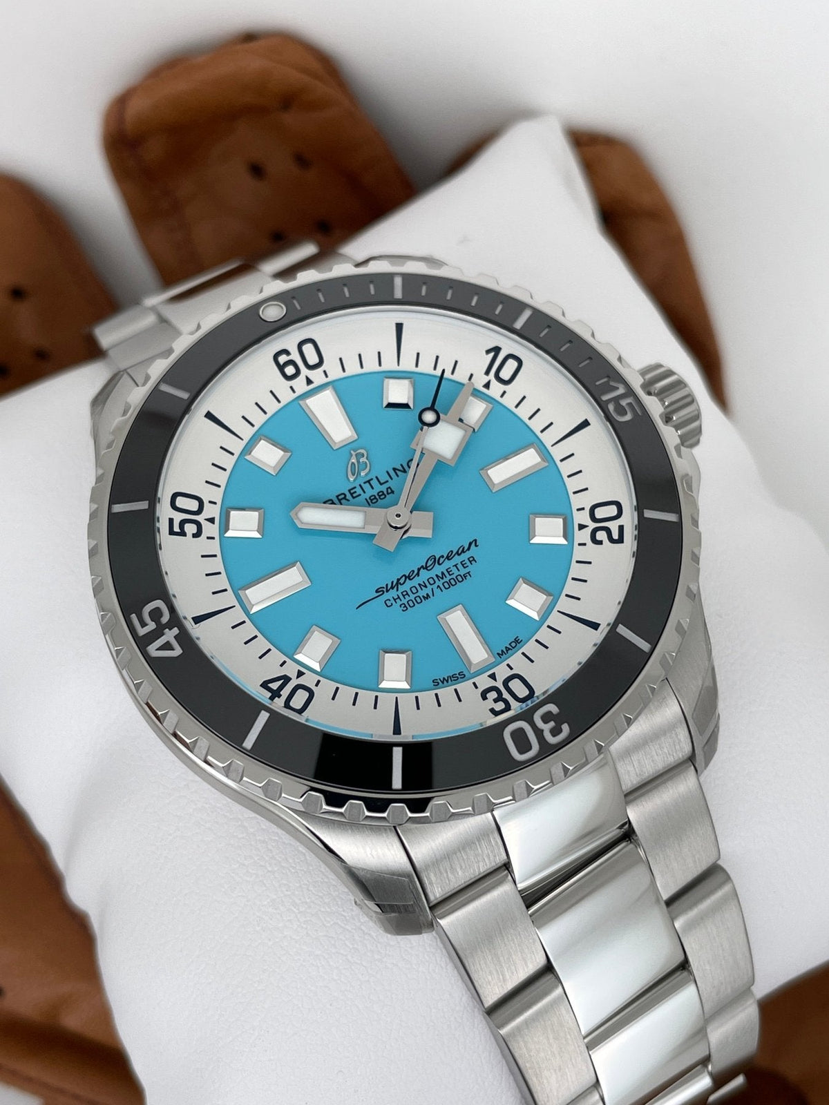 Orologio Breitling Superocean con lunetta nera e quadrante turchese su bracciale acciaio