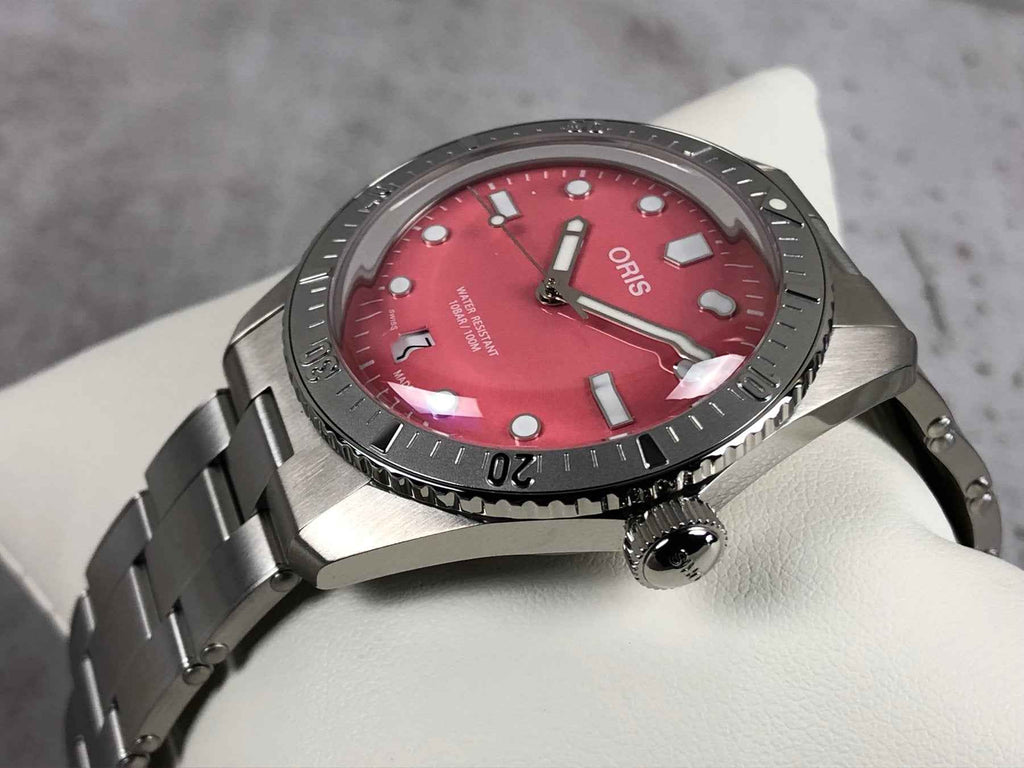 Orologio subacqueo ORIS con quadrante rosso e corona; bracciale in acciaio a maglie.