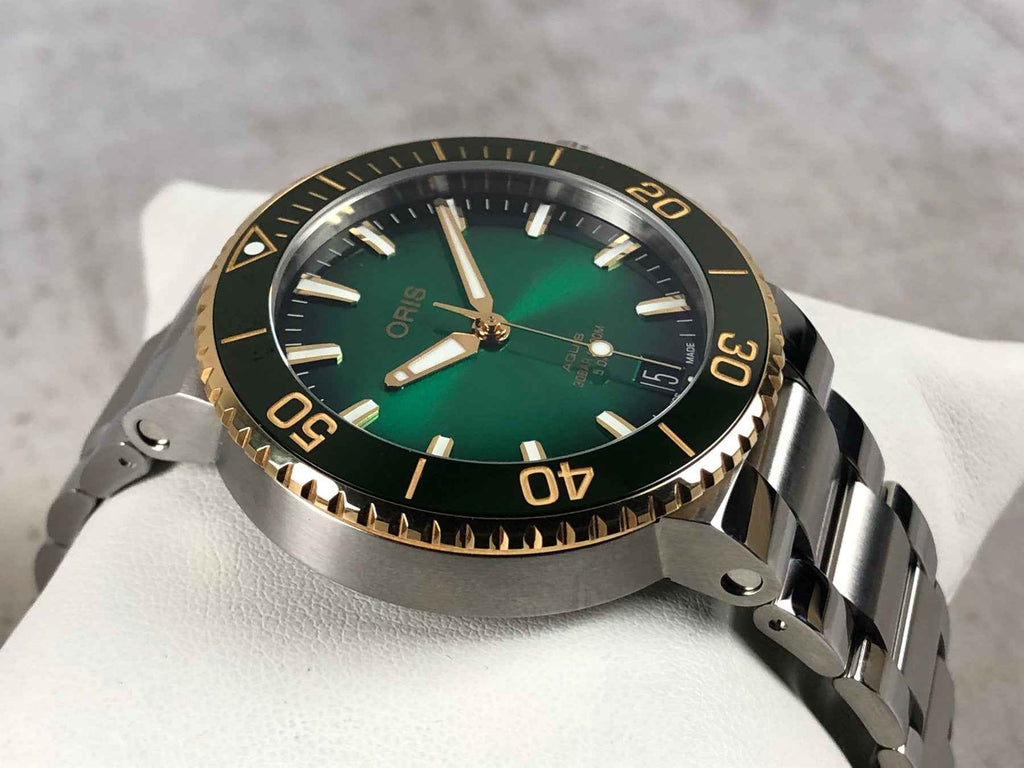 Orologio subacqueo ORIS con quadrante verde, ghiera oro e cinturino in acciaio