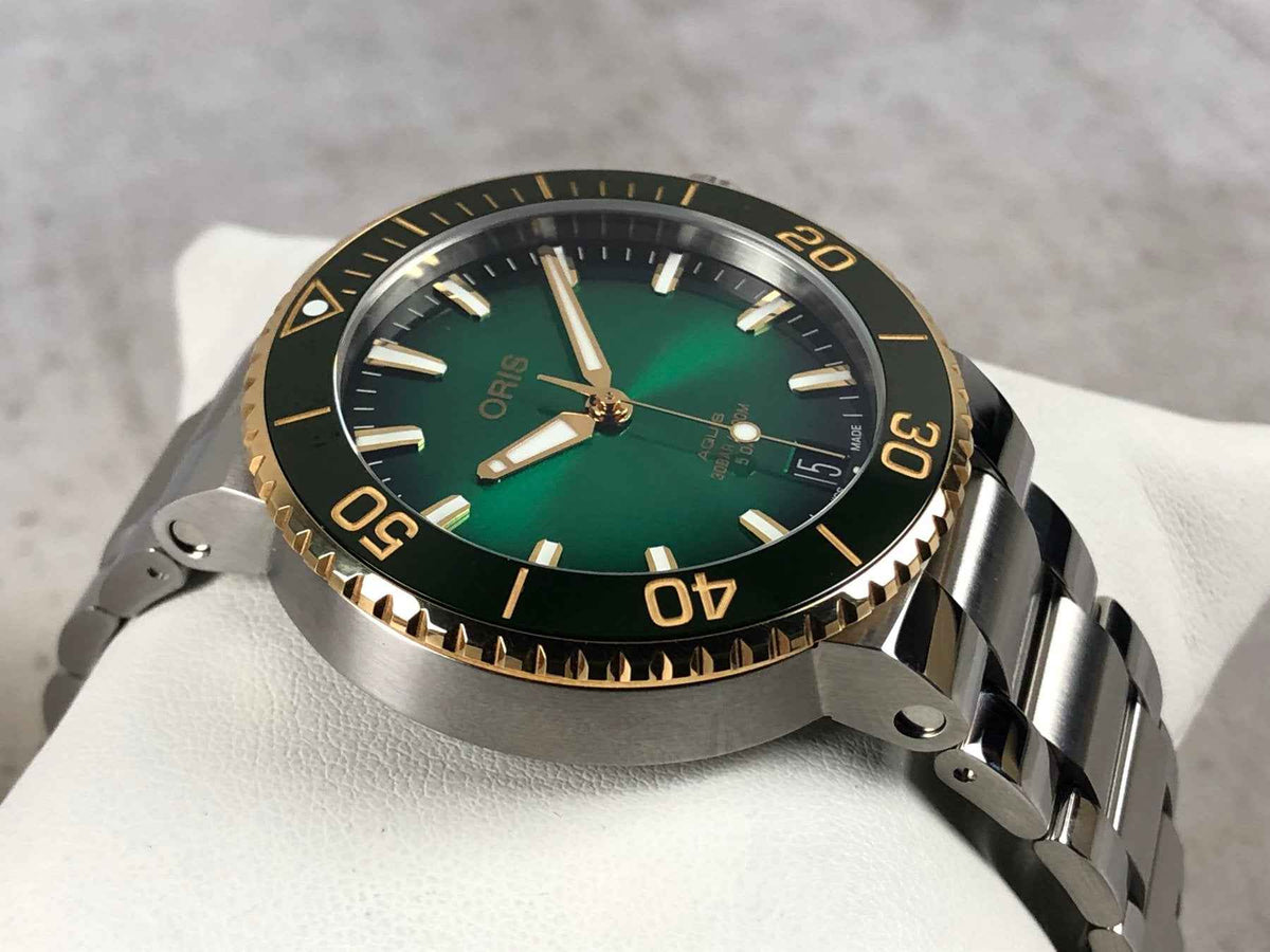 Orologio subacqueo ORIS con quadrante verde, ghiera oro e cinturino in acciaio
