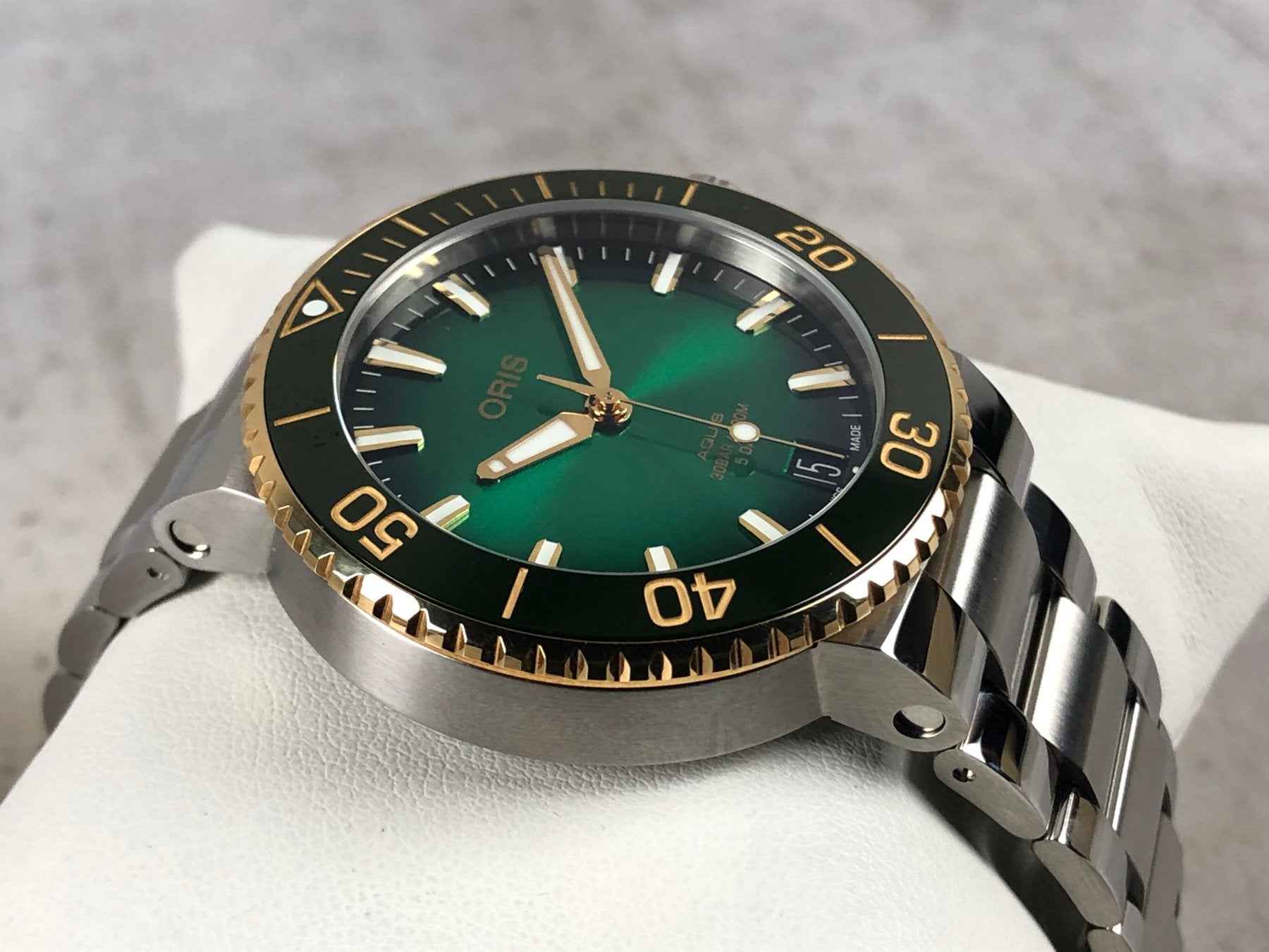 Orologio subacqueo ORIS con quadrante verde, ghiera oro e cinturino in acciaio