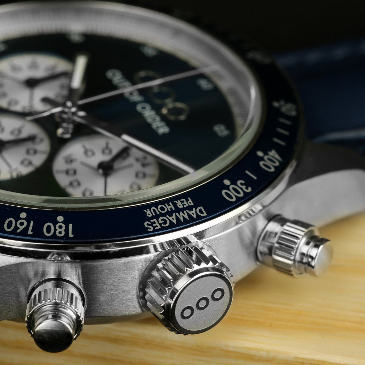 Dettaglio dell’orologio: ghiera blu con indicazioni, pulsanti cromati e cinturino in pelle blu.
