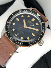 Orologio sub con quadrante blu scuro, indici e lancette dorati, cinturino pelle marrone.