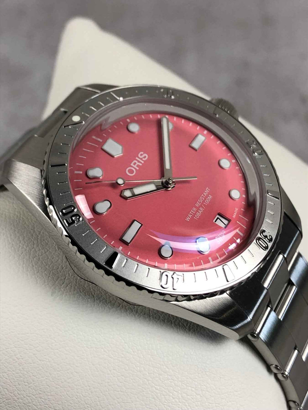 Orologio subacqueo ORIS con quadrante rosso, lancette luminose e bracciale in acciaio.