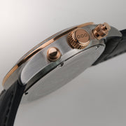 Lato della cassa con viti e pulsanti dorati su orologio con cinturino nero.