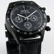 Orologio cronografo con quadrante nero, tre contatori e pulsanti laterali, cinturino pelle nera