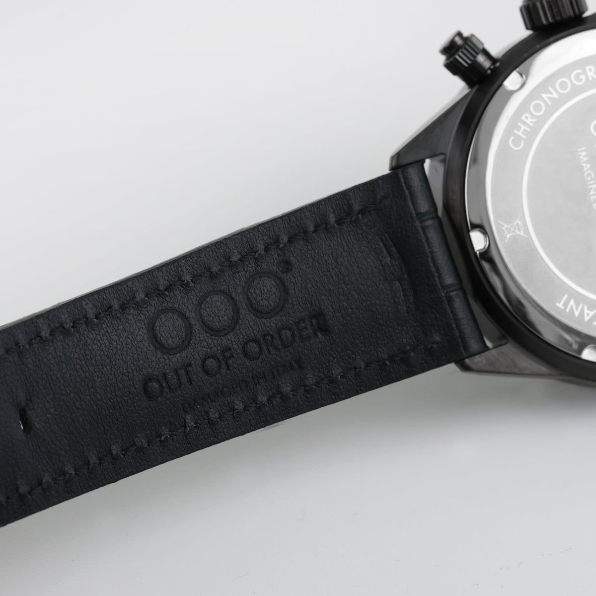 Cinturino in pelle nera con rilievo OUT OF ORDER, bordo cucito e fibbia scura