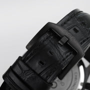 Cinturino in pelle nera con fibbia e passanti, texture in rilievo e chiusura scura