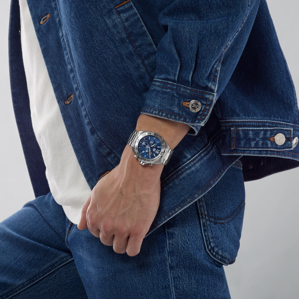 Orologio TAG Heuer al polso con bracciale in acciaio e quadrante blu cronografo.