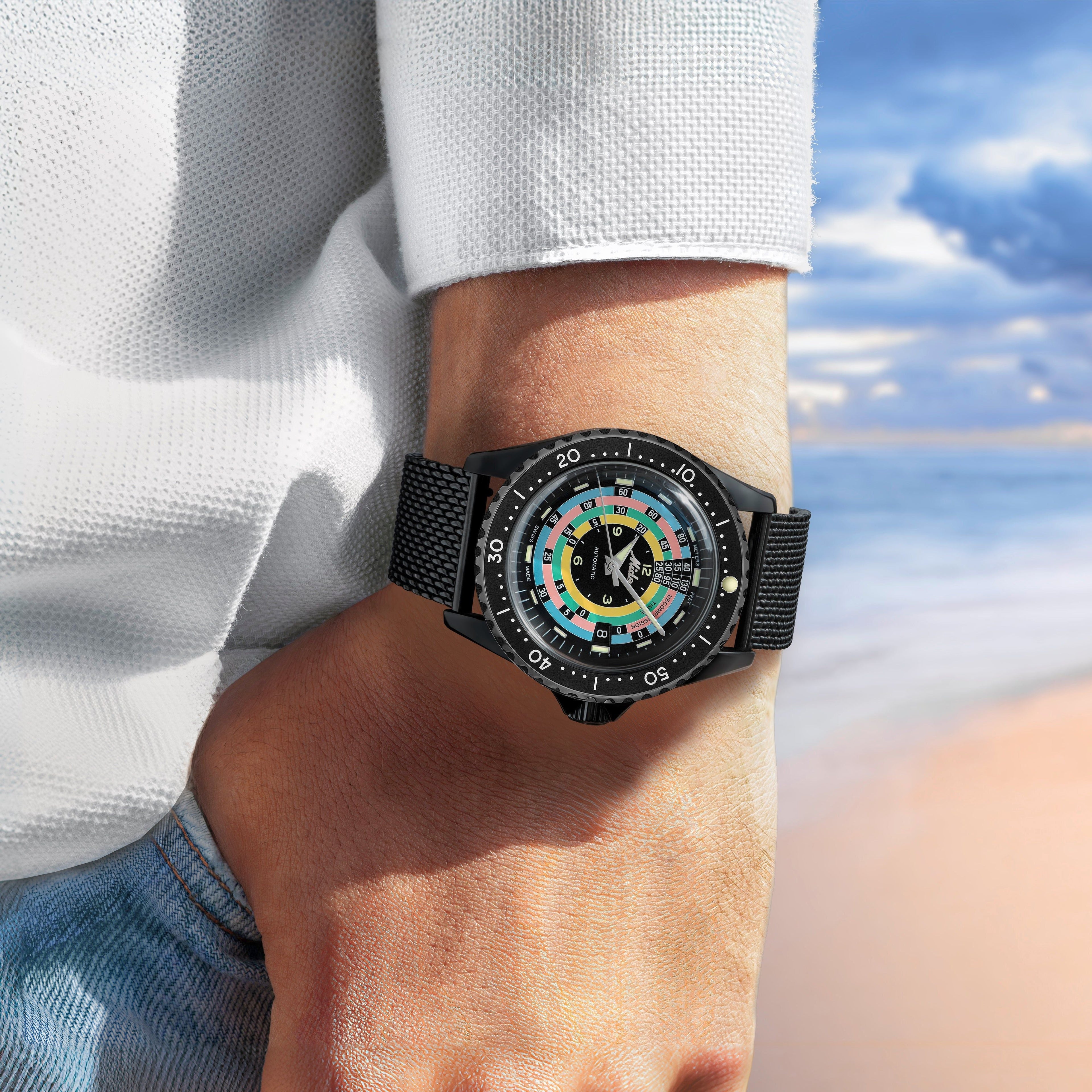 Orologio con cinturino nero a maglia e quadrante multicolore su polso