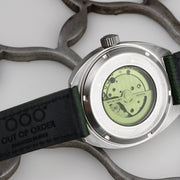 Fondello dell’orologio automatico in acciaio con movimento verde e cinturino in pelle verde.
