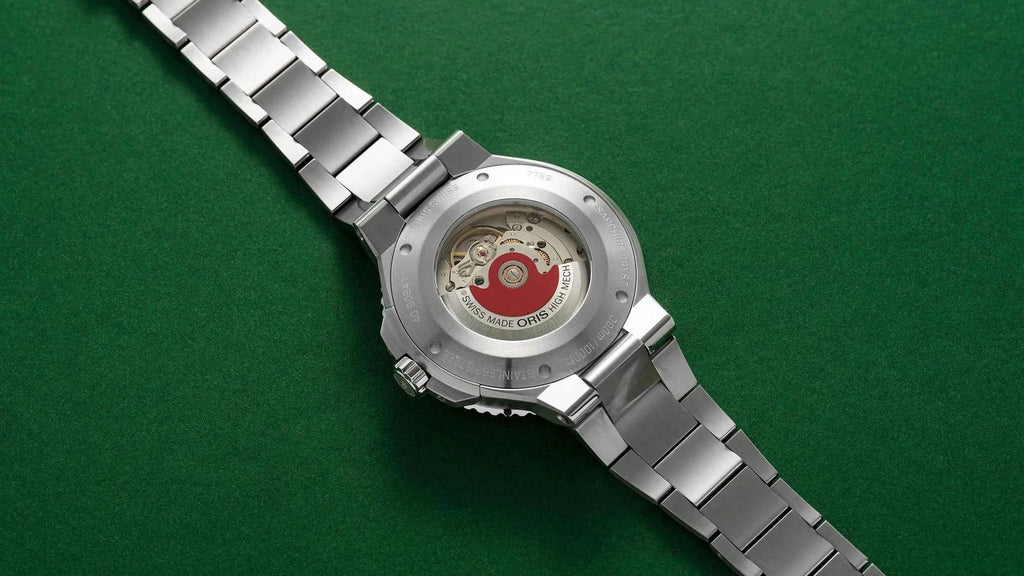 Orologio con fondello esposto e bracciale in acciaio, visto dall’alto.