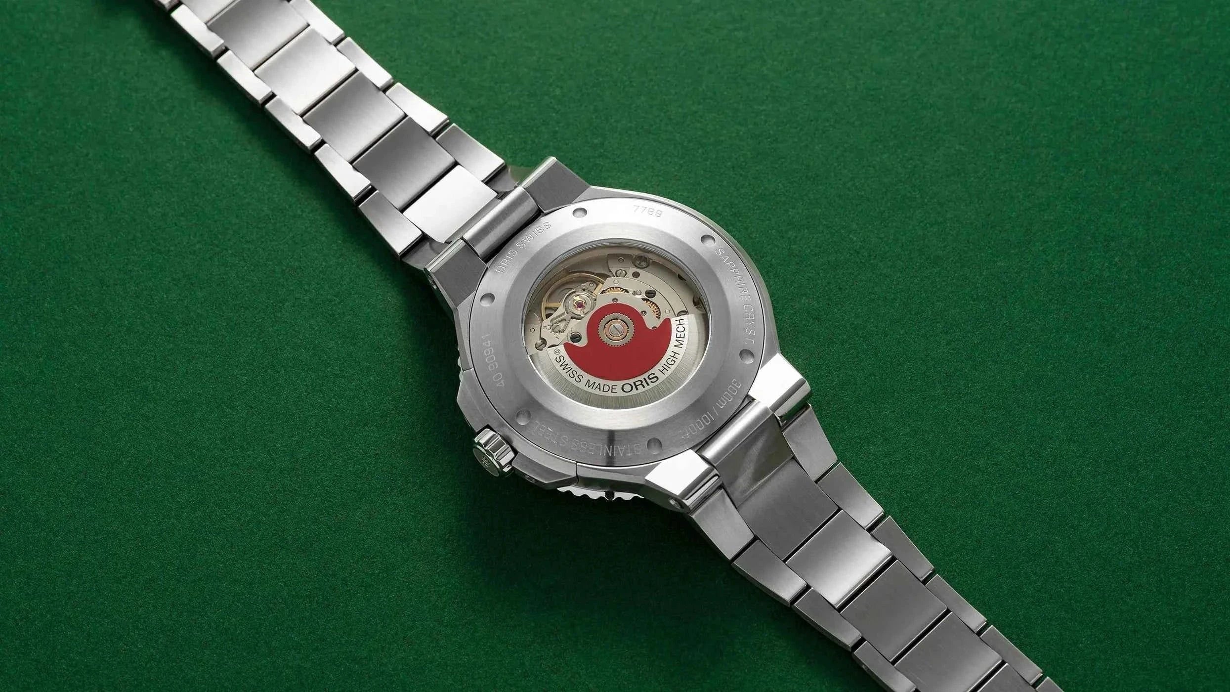 Orologio con fondello esposto e bracciale in acciaio, visto dall’alto.
