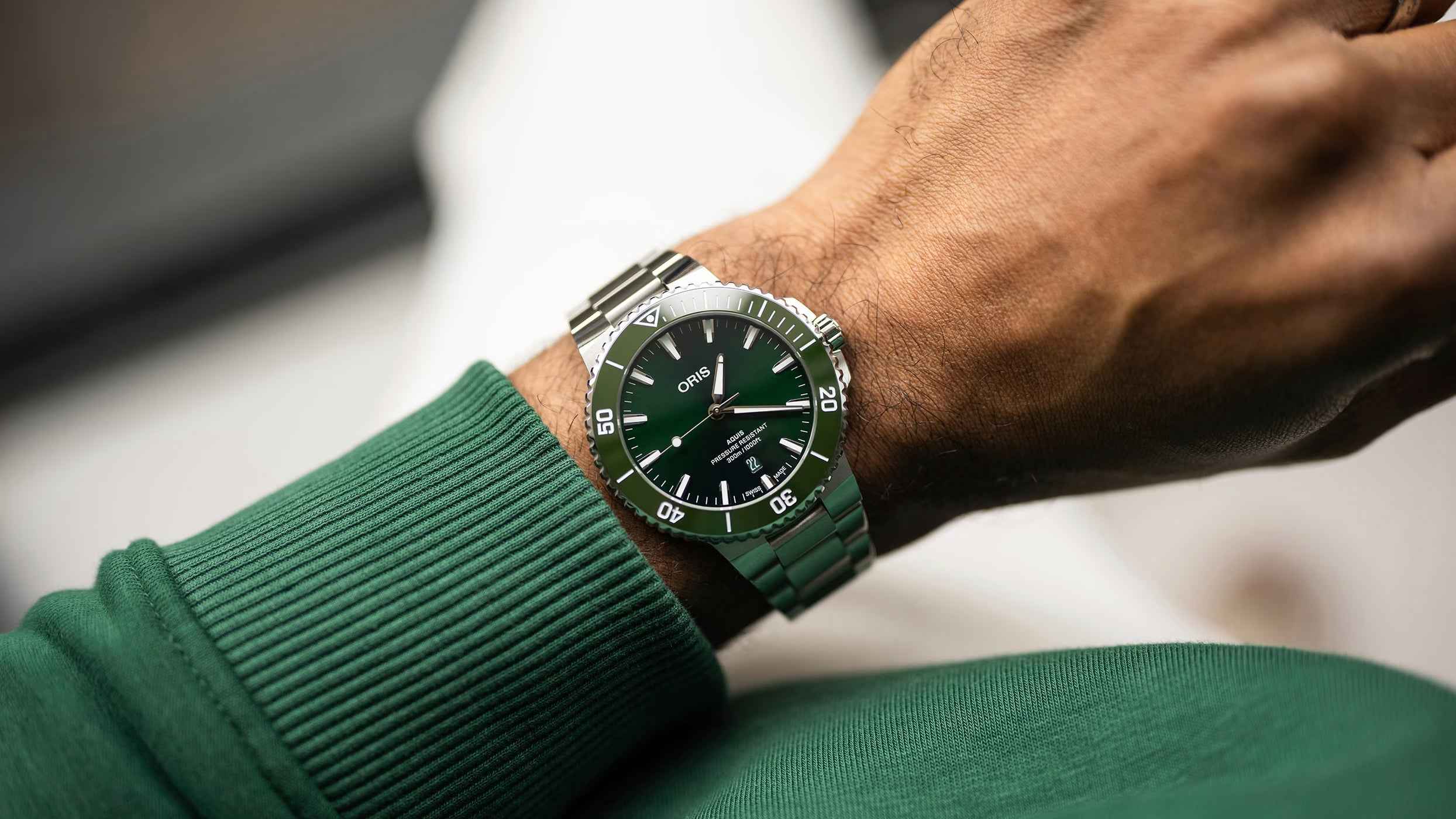 Orologio subacqueo con quadrante verde e bracciale in acciaio, indossato al polso.