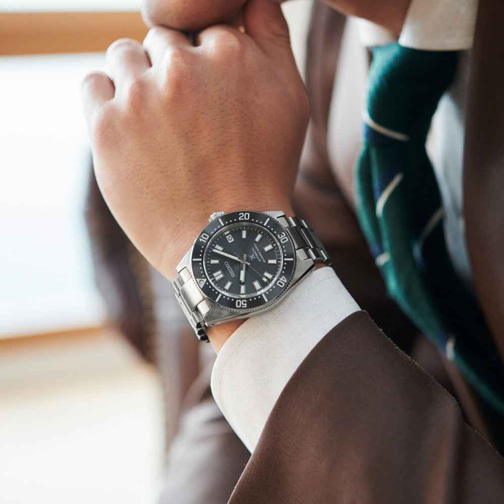 Orologio subacqueo in acciaio indossato al polso, quadrante nero con datario.