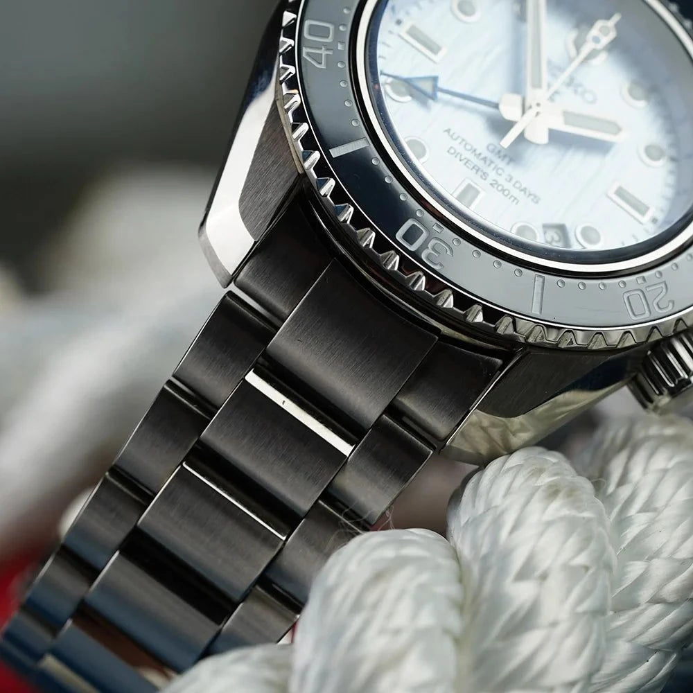 Dettaglio orologio Seiko: bracciale in maglie d’acciaio e lunetta nera con tacche