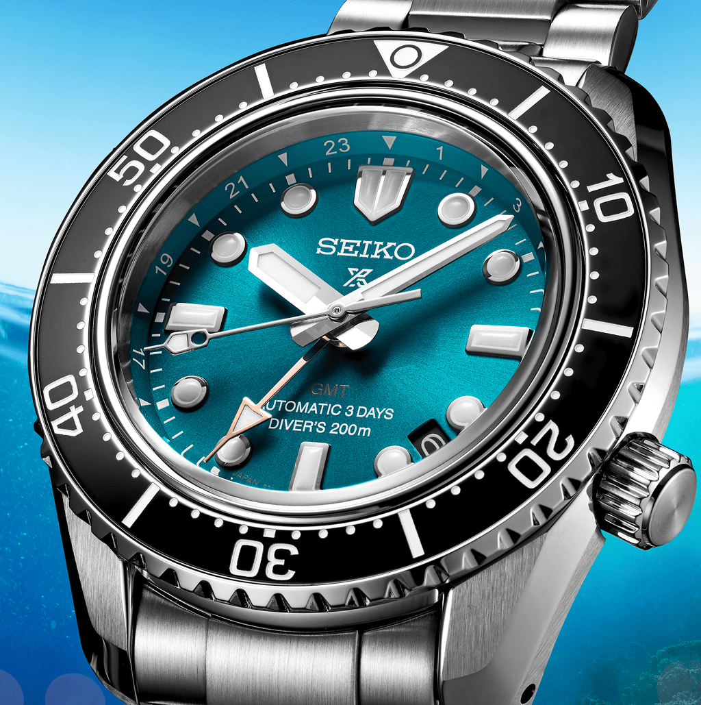 Orologio diver GMT: quadrante blu-verde, lancette e indici luminosi, lunetta nera.