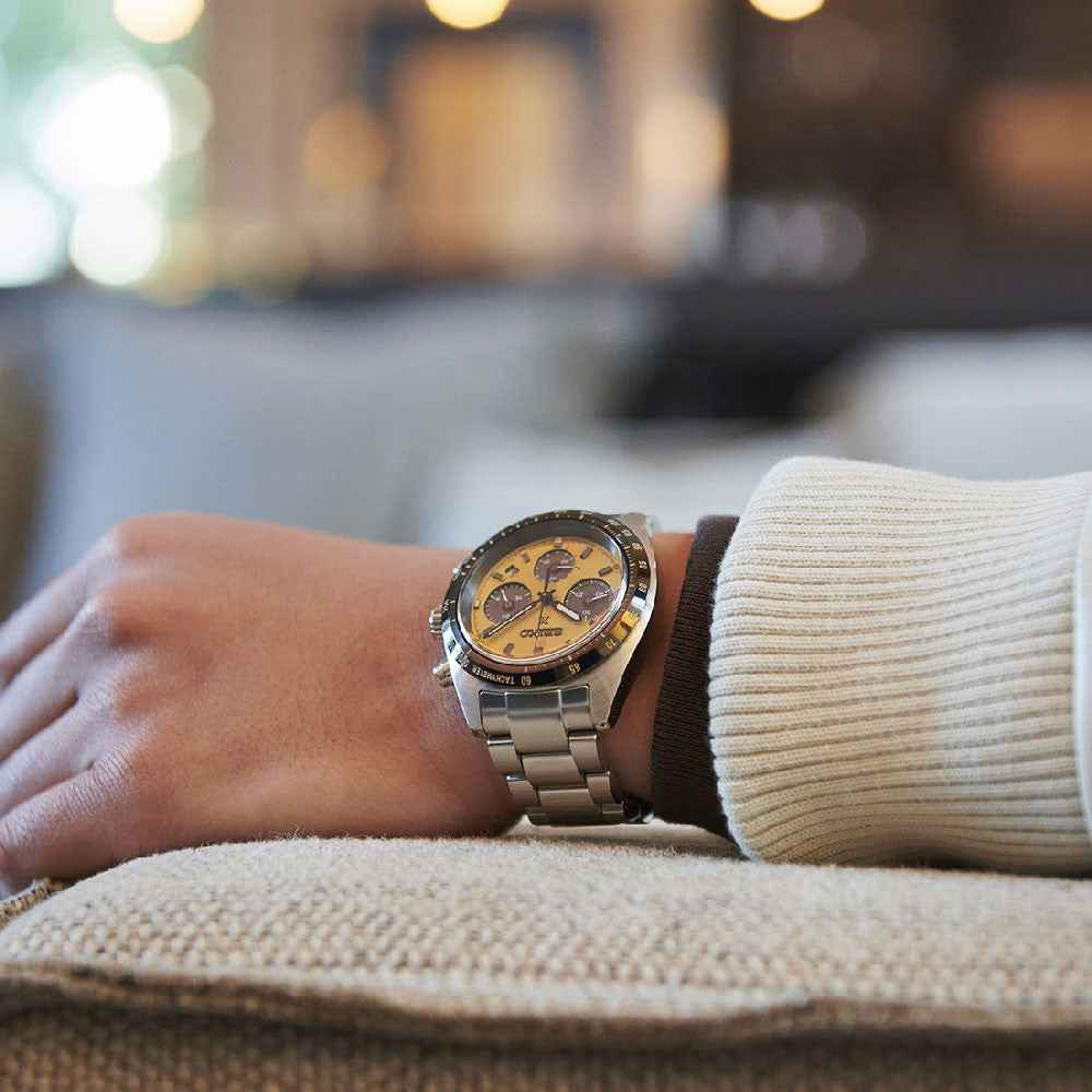 Orologio cronografo con quadrante giallo oro e bracciale in metallo al polso