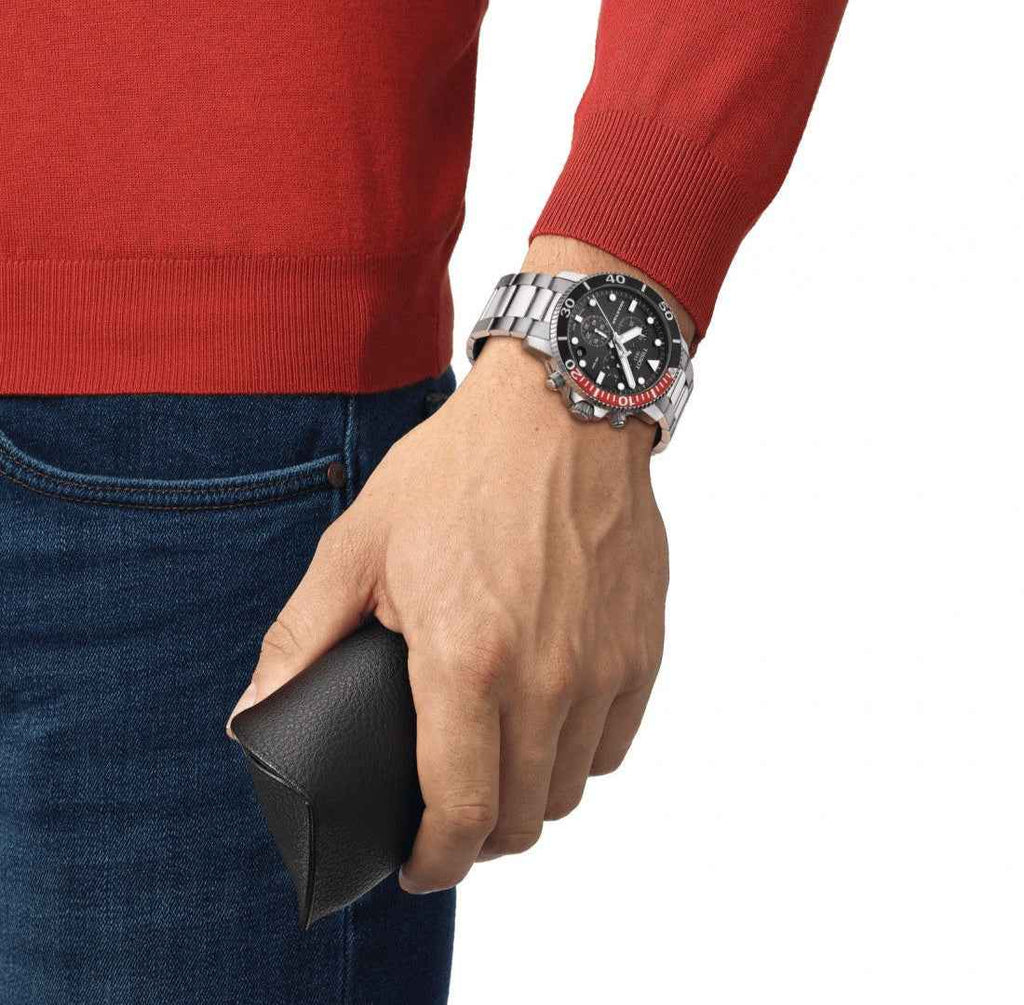 Orologio subacqueo nero con lunetta rossa su polso, bracciale d’acciaio