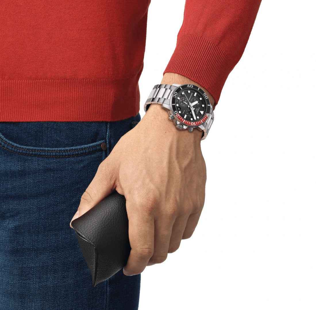 Orologio subacqueo nero con lunetta rossa su polso, bracciale d’acciaio