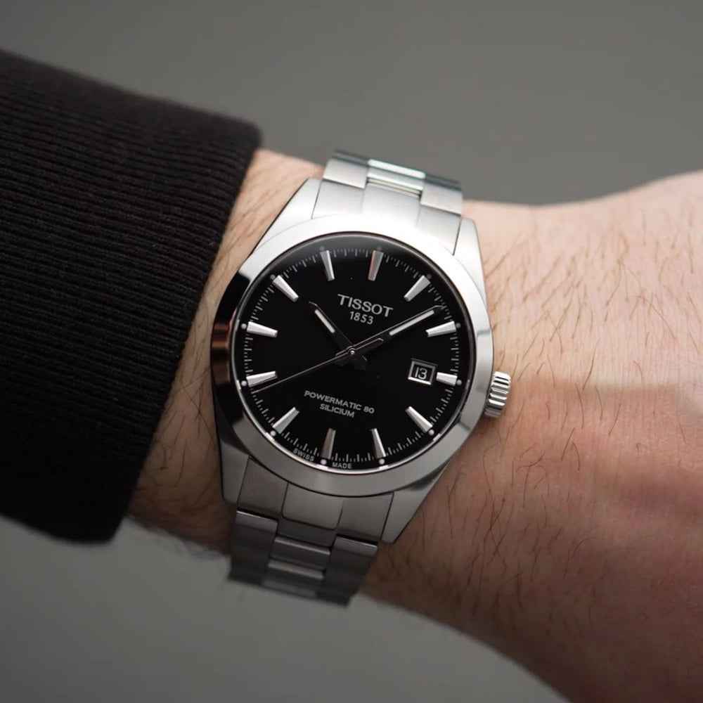 Orologio Tissot automatico al polso, quadrante nero e bracciale d’acciaio metallico