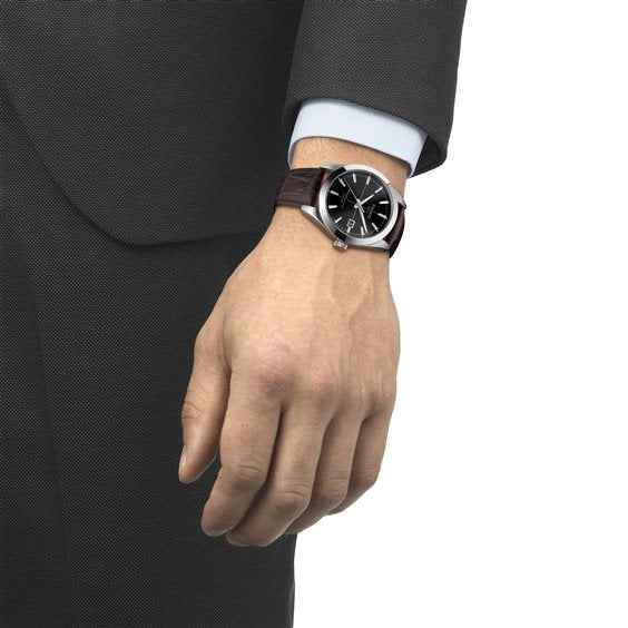 Orologio Tissot automatico al polso, quadrante nero e cinturino in pelle scura