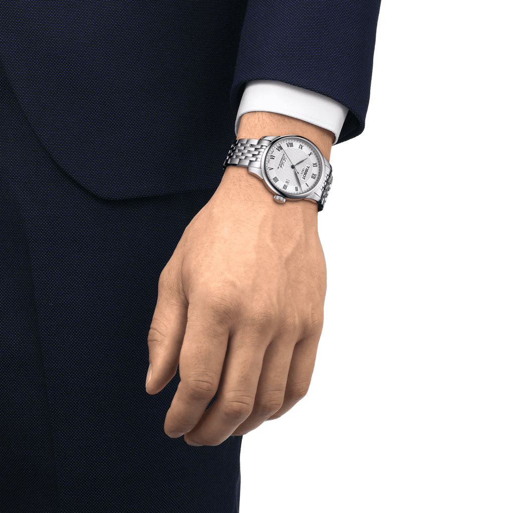 Orologio Tissot al polso con bracciale in acciaio e quadrante chiaro, su manica scura