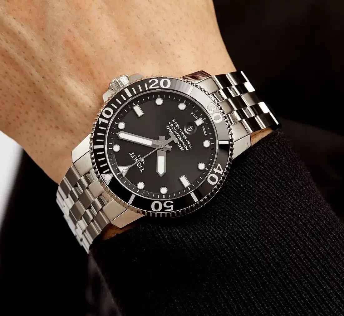 Orologio subacqueo con cinturino in acciaio su polso, quadrante nero e indici
