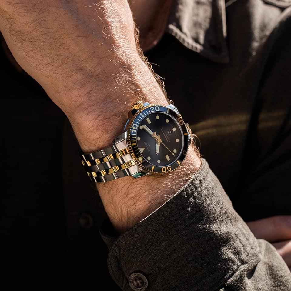 Orologio subacqueo bicolore su polso, quadrante nero con indici oro
