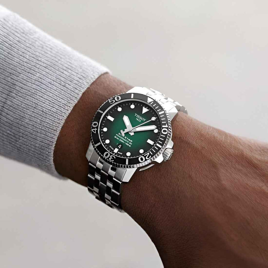 Orologio Tissot subacqueo con quadrante verde e bracciale in acciaio sul polso