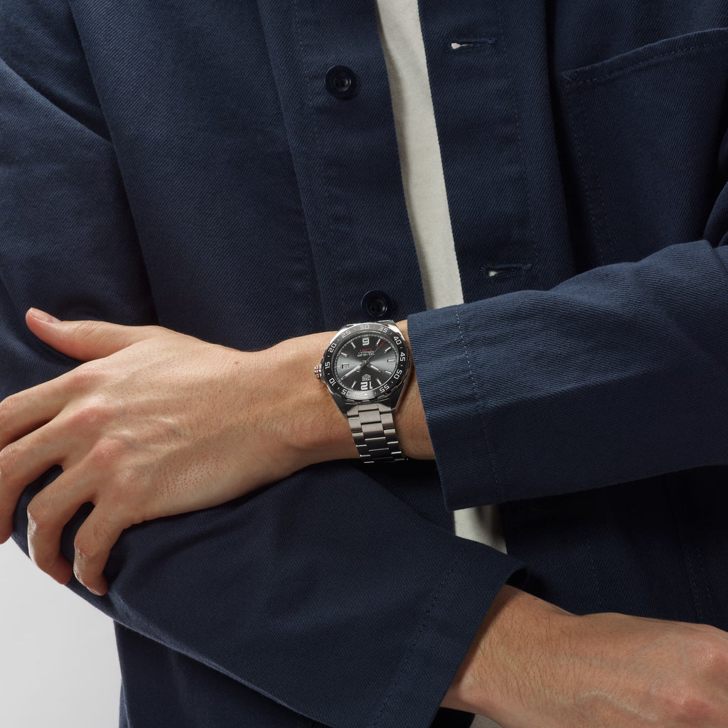Orologio TAG Heuer al polso con bracciale in acciaio e quadrante nero.