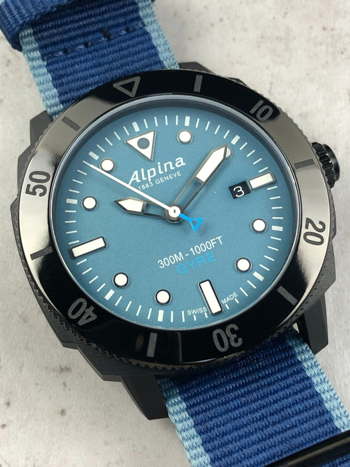 Orologio Alpina subacqueo con quadrante blu, indici luminosi e cinturino NATO a righe