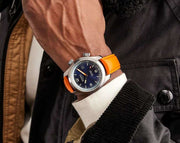Orologio da uomo al polso con quadrante blu e cinturino arancione in caucciù