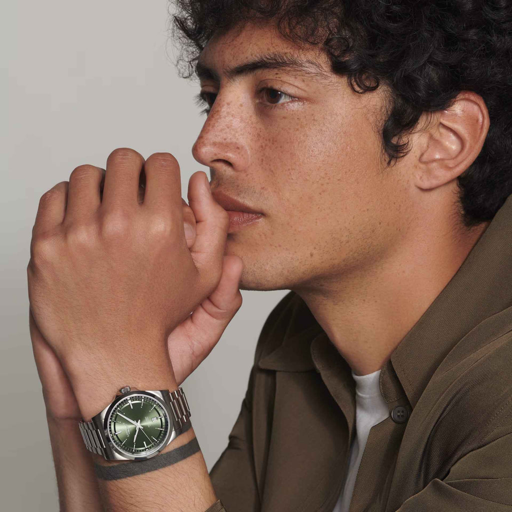 Orologio con bracciale in acciaio e quadrante verde indossato al polso, vista laterale