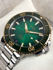 Orologio subacqueo ORIS con quadrante verde, ghiera nera con numeri oro e bracciale acciaio