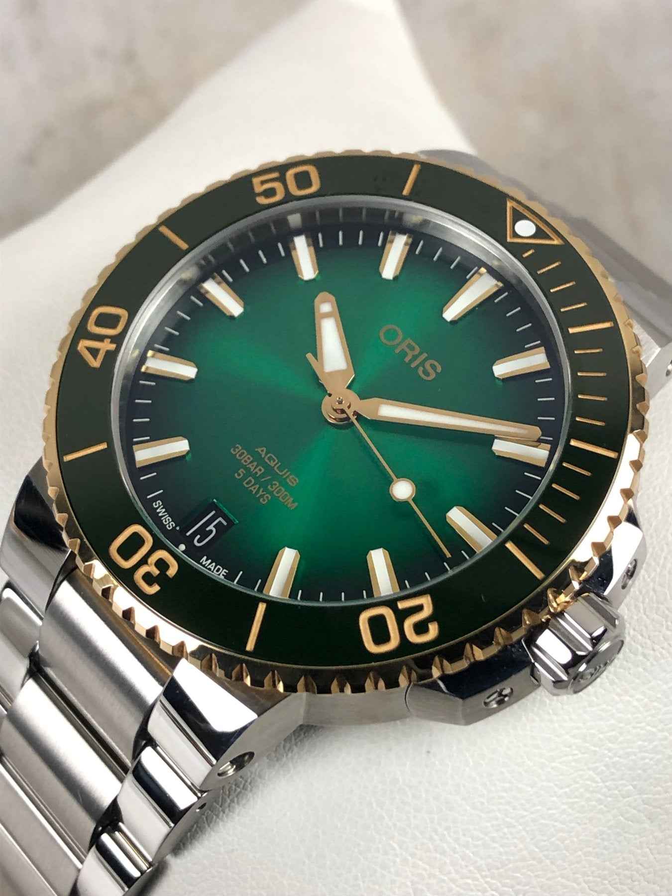 Orologio subacqueo ORIS con quadrante verde, ghiera nera con numeri oro e bracciale acciaio