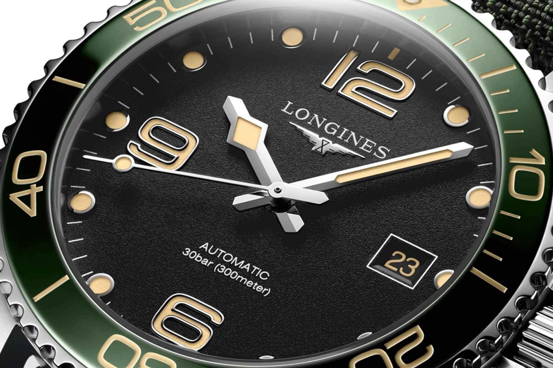 Primo piano quadrante nero HydroConquest, indici e lancette oro, data 23, ghiera verde