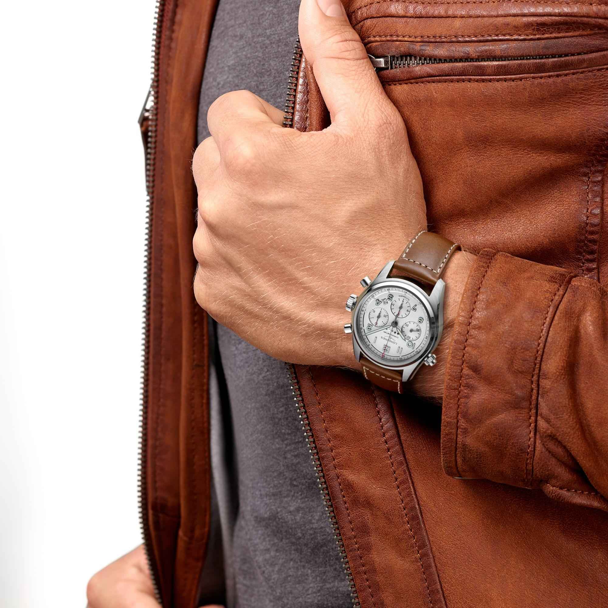 Orologio automatico al polso: quadrante argento, cinturino in pelle marrone, abito in pelle.