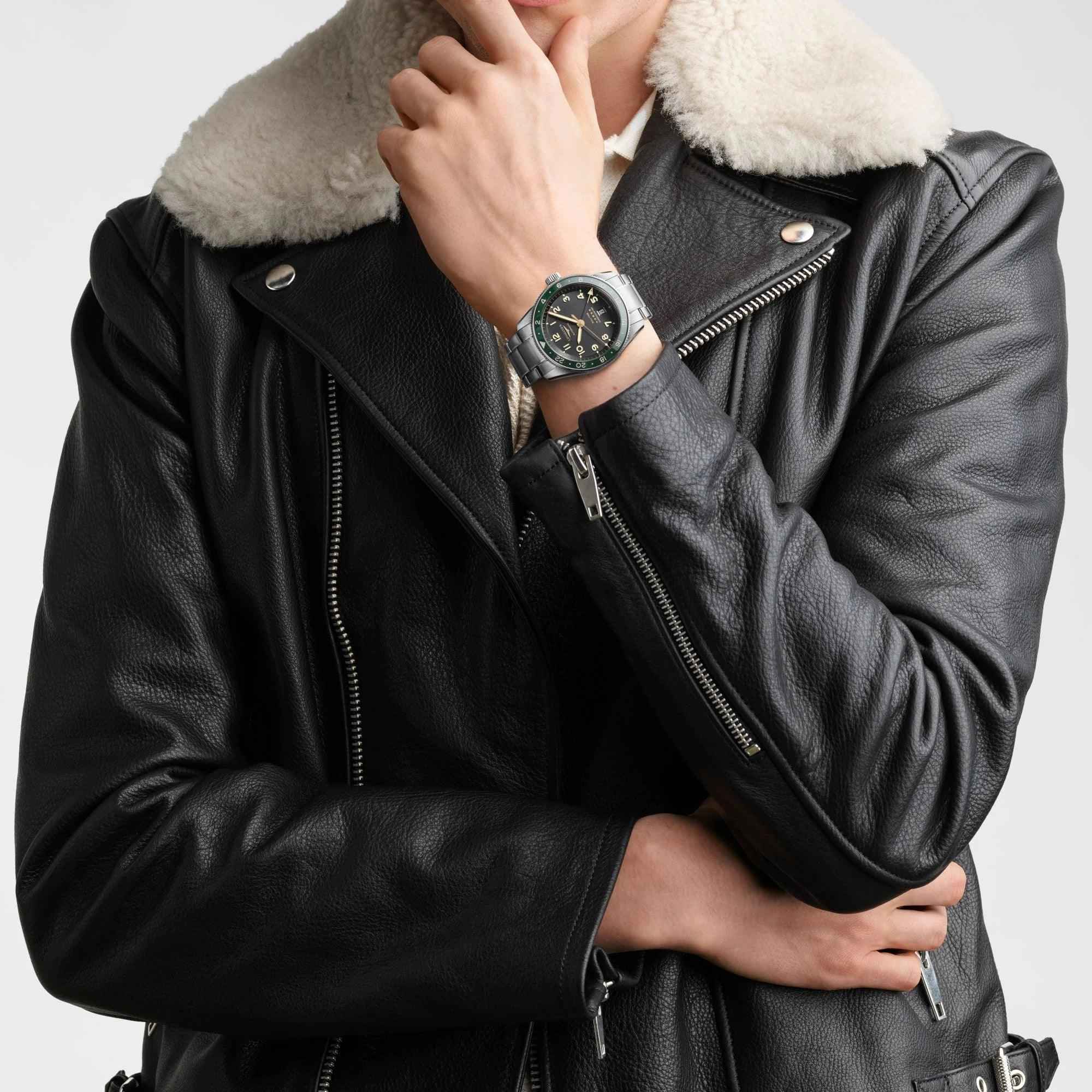 Orologio Longines al polso con quadrante nero e cinturino d’acciaio, indossato con giacca in pelle.