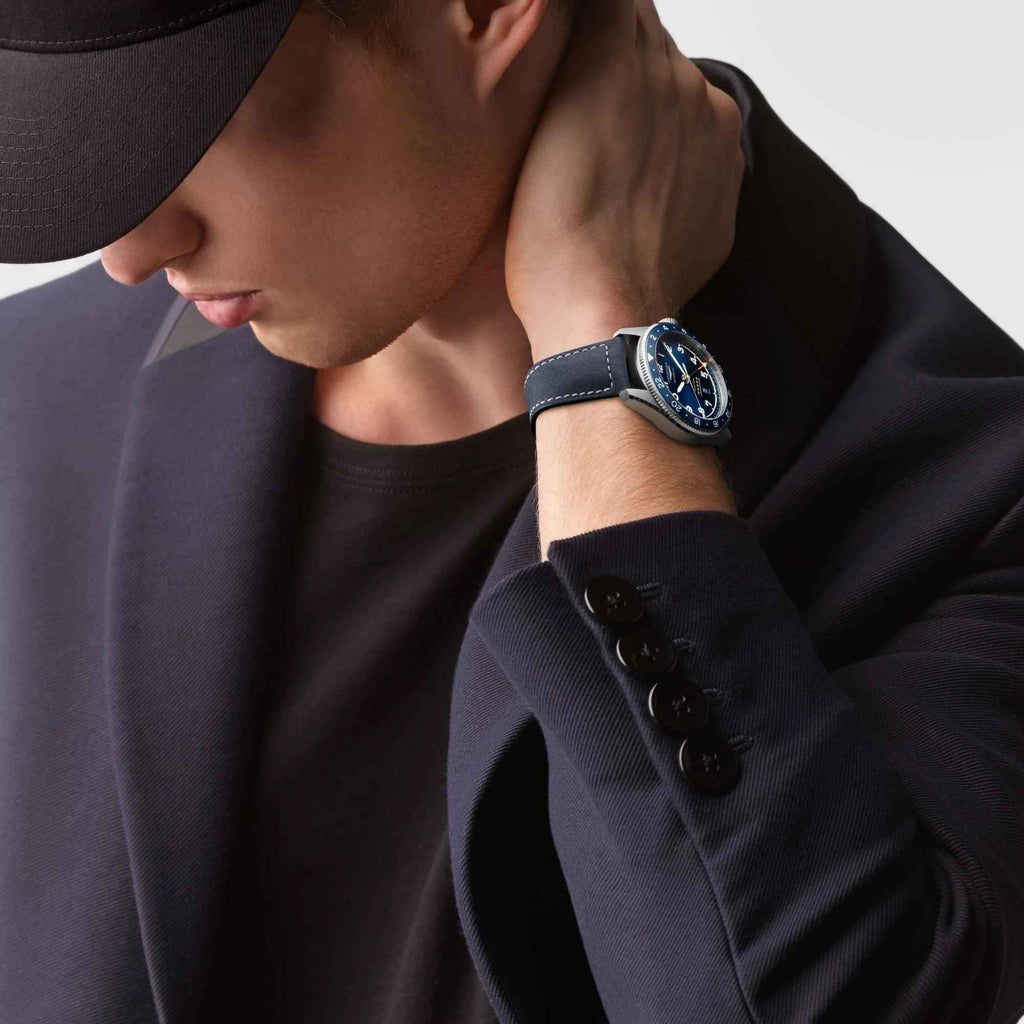 Orologio in acciaio e cinturino in pelle blu al polso con abito scuro