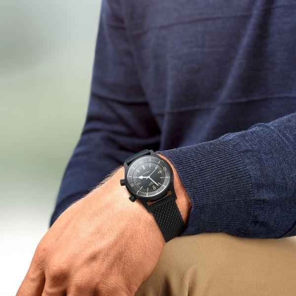 Orologio nero indossato al polso con cinturino a trama e quadrante nero