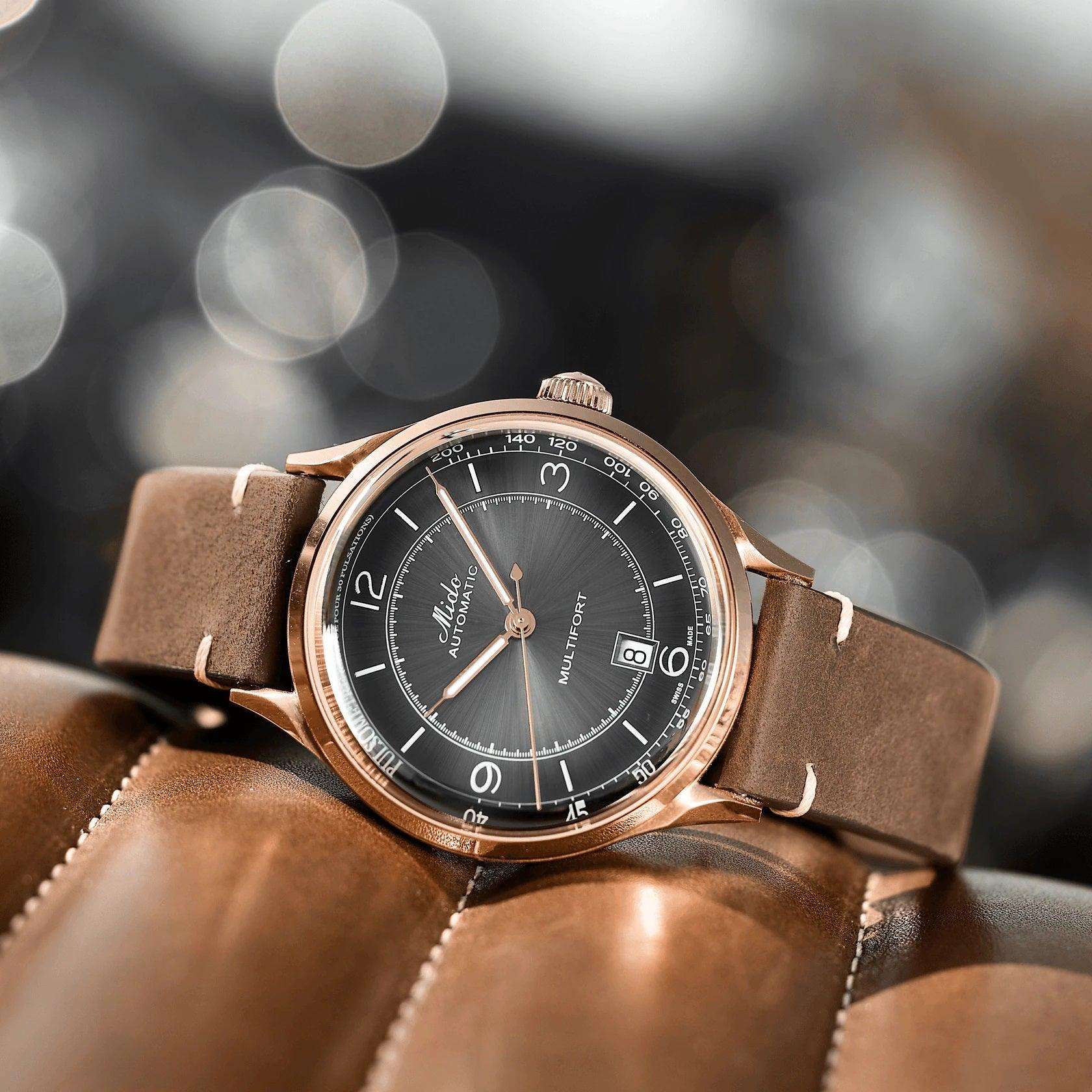 Orologio automatico con quadrante nero e cassa rosé su cinturino in pelle marrone.