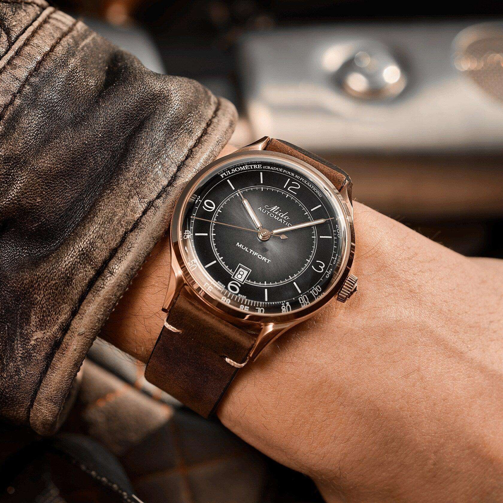 Orologio automatico con quadrante nero, cassa rosé e cinturino in pelle marrone.