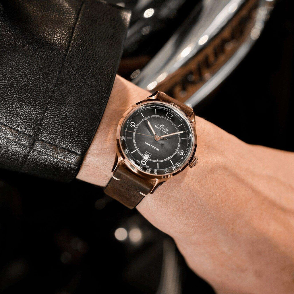 Orologio automatico su polso con quadrante nero, cassa rosé e cinturino in pelle marrone.
