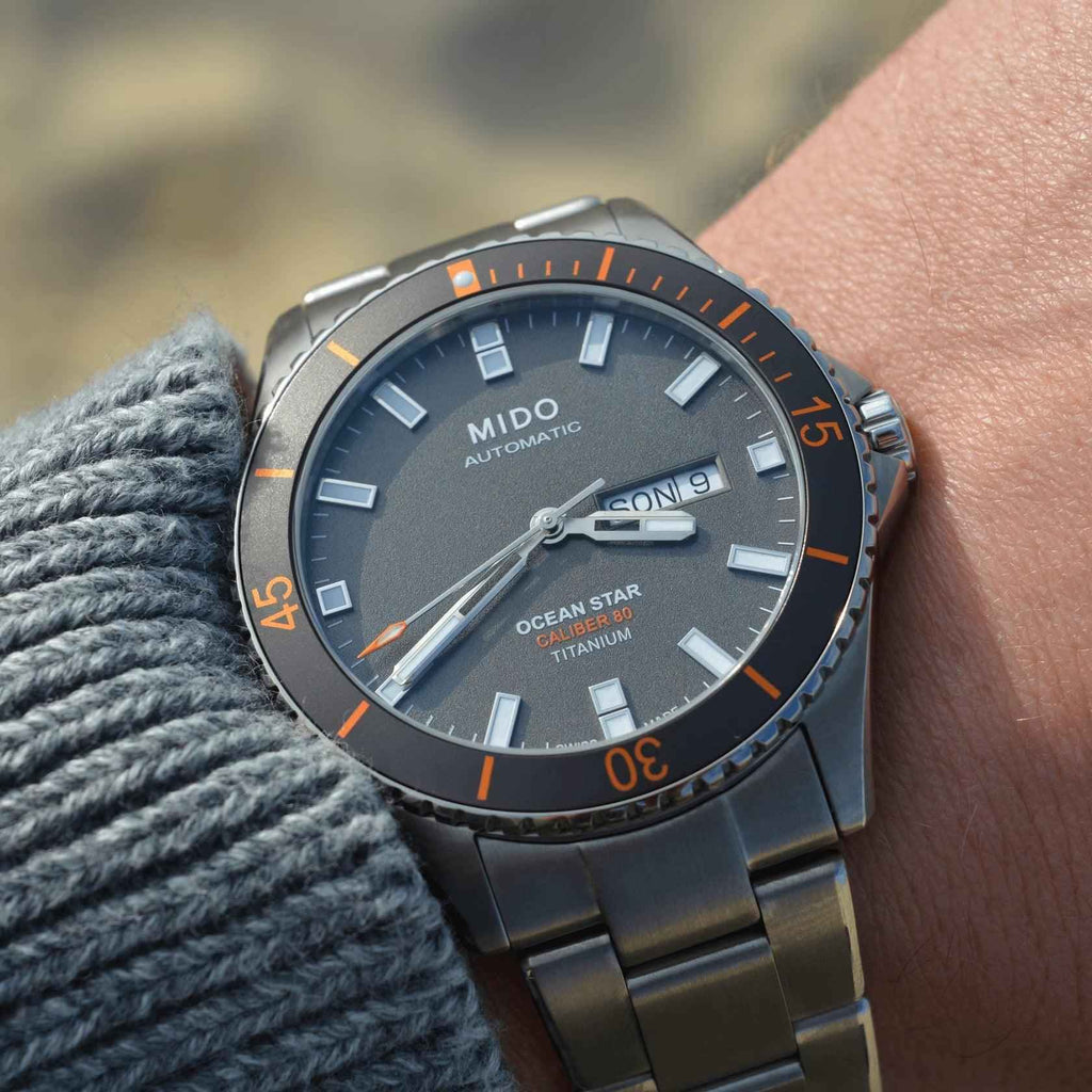 Orologio con quadrante nero e ghiera arancione, cinturino in titanio